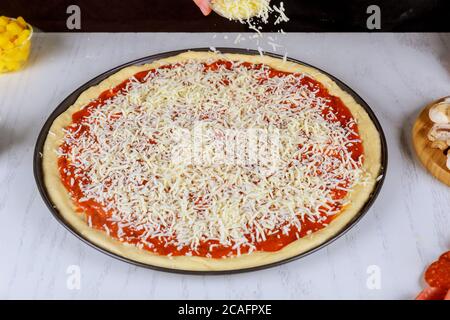 Chef sprinkling pizza with shredded mozzarella cheese. Stock Photo
