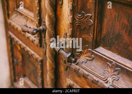 Close-up of metal handles on brown door with raised carvings Stock Photo