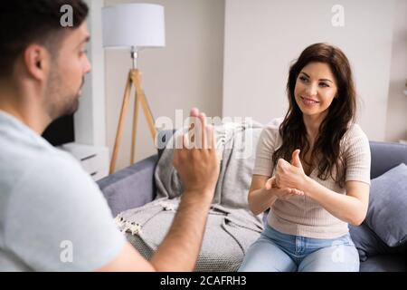 Young Deaf People Using Sign Language At Sofa Stock Photo