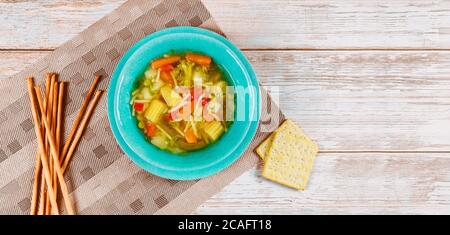 Diet soup with healthy vegetables, crackers and italian bread sticks on wooden table. Stock Photo