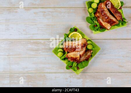 Delicious BBQ pork ribs with cucumber, green salad and tangy BBQ sauce. Stock Photo