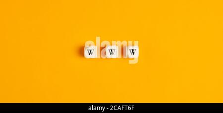 WWW inscription on wooden blocks against yellow background. Flat lay view. Stock Photo