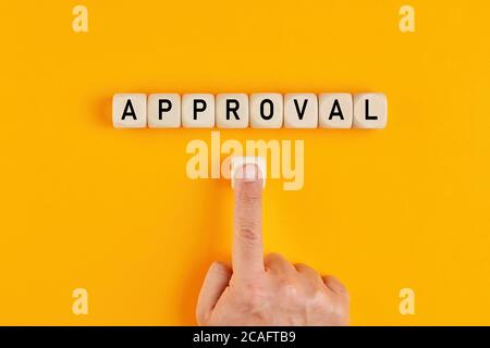 The word approval written on wood blocks with a male hand pushing the button. Concept of approving in business or finance. Stock Photo