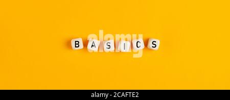Basics word written on wood blocks on yellow background with flat lay view. Back to basics or simplifying business concept. Stock Photo