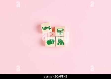 The word blog and icons related to blogging are carved on wooden blocks on pink background. Concept of blog and blogging process. Stock Photo