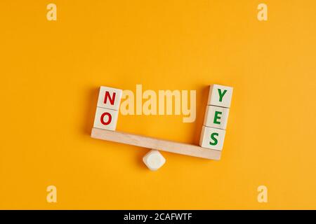 Yes and no inscription on wooden cubes on a seesaw with yes outweighs no. The concept of positivity or positive attitude in life. Stock Photo