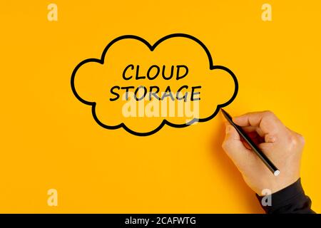 Male hand drawing a cloud with the words cloud storage written in it. Concept of digital data storage. Stock Photo