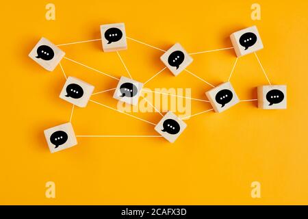 Concept of online communication or social networking. Wooden cubes with speech bubbles linked to each other with lines. Stock Photo