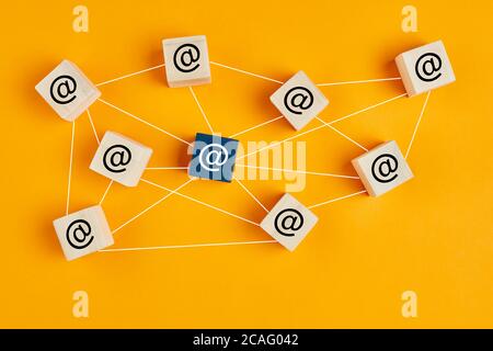 Email at symbol on wooden cubes linked each other with lines as network on yellow background. Email traffic or chain mail concept Stock Photo