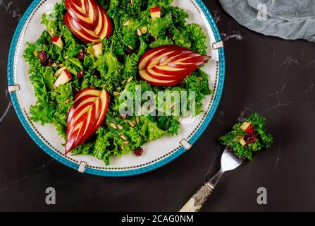 Beautiful fresh kale salad with sliced red apple and cranberry. Stock Photo