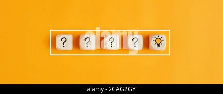 The process of problem solving or idea formation. Question mark and light bulb icons on wooden cubes on yellow background. Stock Photo