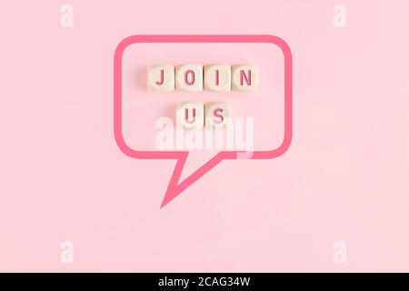 Join us message on wooden cubes framed by a speech bubble on pink background with copy spce. Stock Photo