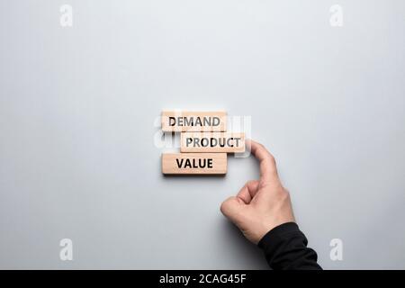 Product marketing concept. Business marketing words demand, product and value written on wooden blocks with a male hand placing the word product. Stock Photo