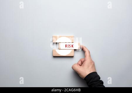 Male hand pushing the wooden block with the word risk written on it. Risk taking behavior, ambition, business investment decision or determination con Stock Photo