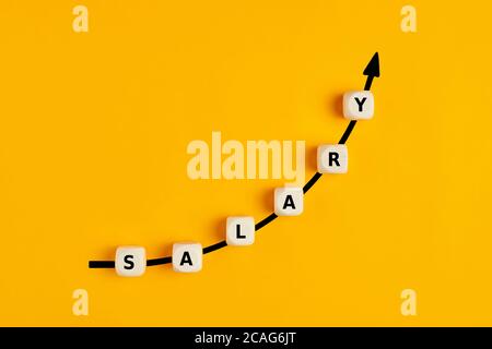 Salary raise or wage increase concept with the word salary written on wooden blocks with an ascending arrow graph Stock Photo