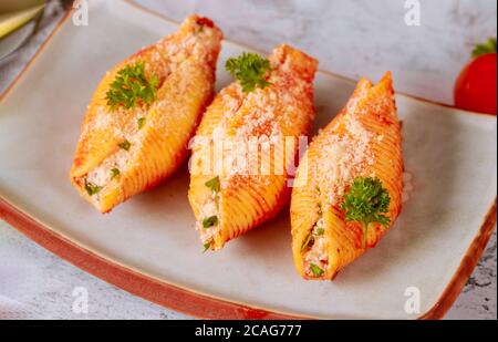 Pasta shells stuffed with ricotta, meat and parmesan on plate with parsley. Close up. Stock Photo