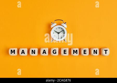 Alarm clock with the word management written on wooden cubes. Concept of time management in business projects or daily life. Stock Photo