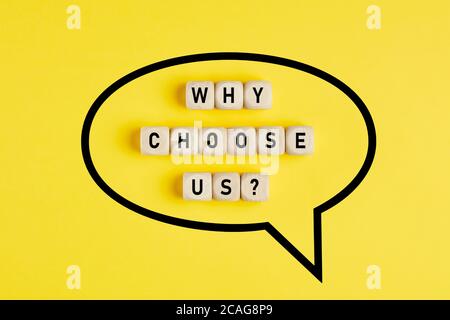 The word why choose us written on wooden cubes framed with a speech balloon on yellow background. Reasons or benefits to choose services or products c Stock Photo