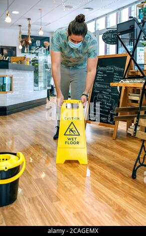 Worker placing wet floor sign after mopping Stock Photo