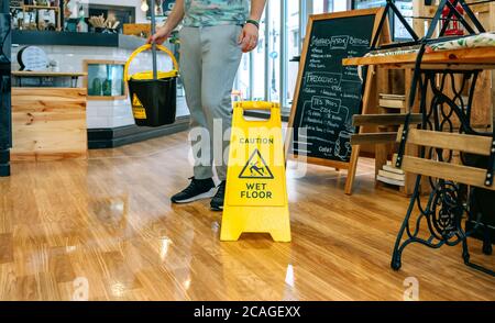 Worker placing wet floor sign after mopping Stock Photo