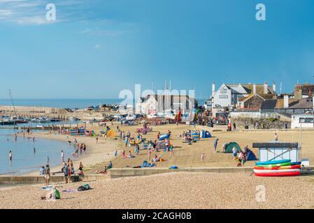 Lyme Regis, Dorset, UK. 7th Aug, 2020. UK Weather: Beachgoers, holidaymakers and families arrive early to secure a spot on the sandy beach at the seaside resort of Lyme Regis on the hottest day of the year. Temperatures are set to soar through the day with reaching record breaking highs forecast as the Saharan heatwave hits the South Coast. Credit: Celia McMahon/Alamy Live News Stock Photo