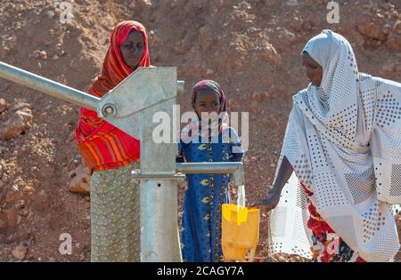13.11.2019, Gabradahidan, Somali Region, Ethiopia - Women filling yellow water canisters at a water pump connected to a cistern. Hydraulic engineering Stock Photo