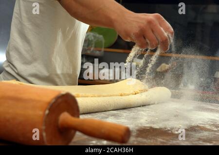 Confectioner sprinkles the flour while kneading the dough and empty space for text Stock Photo
