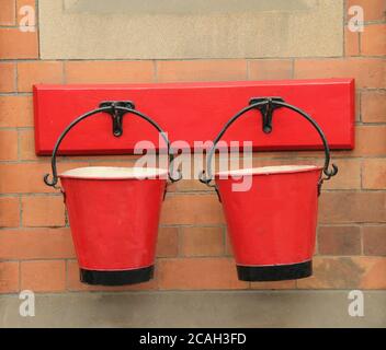 Two Red Vintage Fire Buckets Hanging on a Brick Wall. Stock Photo