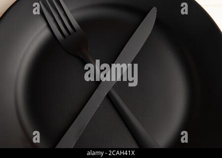 Overhead shot of black fork and knife on a plate Stock Photo