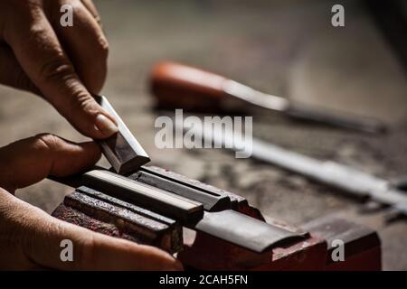 Luthier making a classical guitar bridge plate Stock Photo