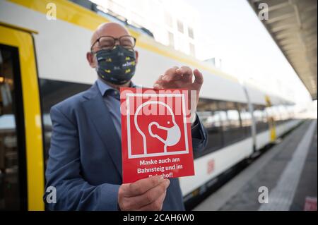 Stuttgart, Germany. 07th Aug, 2020. Winfried Hermann (Bündnis 90/Die Grünen), Minister of Transport of Baden-Württemberg, holds one of the notices in his hand during a press event at which the new new information boards on compulsory masks in trains and stations are presented. Credit: Sebastian Gollnow/dpa/Alamy Live News Stock Photo