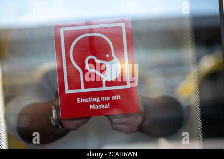 Stuttgart, Germany. 07th Aug, 2020. A man attaches one of the signs saying 'boarding only with a mask' to a train during a press conference presenting the new information boards on mask obligation in trains and stations. Credit: Sebastian Gollnow/dpa/Alamy Live News Stock Photo