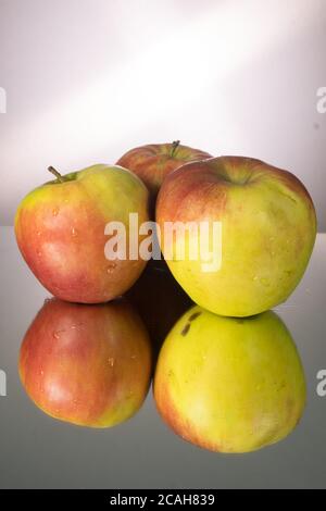 Three red apple on mirroring table. Vertical image with copy space. Stock Photo