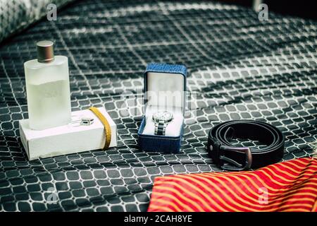 Wedding shoes, belts, watches and bouquet on a white surface. Accessories for the groom on the wedding day. Stock Photo