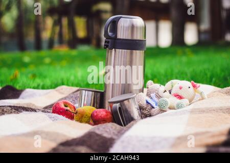 metal thermos with tea in nature. Hot tea in a cup on a camping trip.