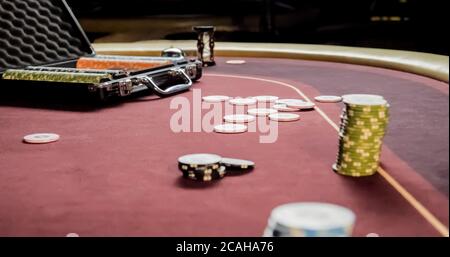 stacks of colorful poker chips and cards in case on red cloth in casino gambling Stock Photo