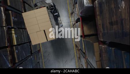 Lifting warehouse worker stacking cardboard boxes on pallets in ...