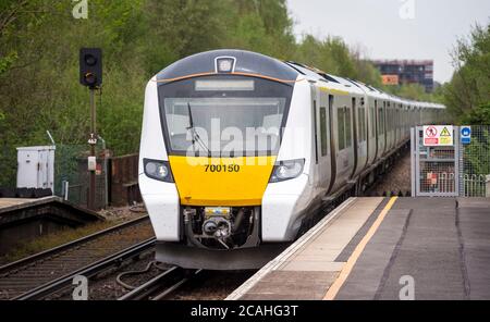 Class 700 passenger train in Thameslink livery approaching a railway station, England. Stock Photo