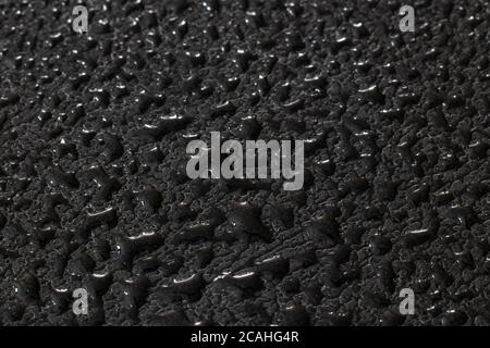 Water droplets on black leather like texture with bright highlights Stock Photo