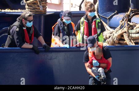 EDITORS NOTE: IMAGE PIXELATED BY PA PICTURE DESK A Border Force officer helps a young boy from a Border Force vessel as a group of people thought to be migrants are brought into Dover, Kent, following a number of small boat incidents in The Channel. Stock Photo