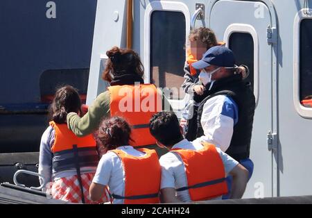 EDITORS NOTE: IMAGE PIXELATED BY PA PICTURE DESK A Border Force officer escorts a young family thought to be migrants from a Border Force vessel after they were brought into Dover, Kent, following a number of small boat incidents in The Channel. Stock Photo