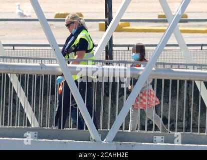 EDITORS NOTE: IMAGE PIXELATED BY PA PICTURE DESK A young girl is escorted by a Border Force officer as groups of people thought to be migrants are brought into Dover, Kent, following a number of small boat incidents in The Channel. Stock Photo