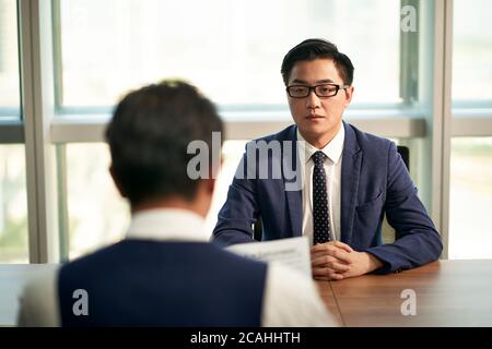 nervous young asian man being interviewed by corporate human resources manager Stock Photo