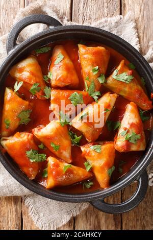 cabbage rolls with meat and rice with tomato sauce and parsley close-up in a bowl on the table. Vertical top view from above Stock Photo