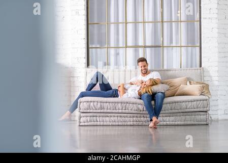 A beautiful young woman lying on the sofa with head on her boyfriends chest. Stock Photo