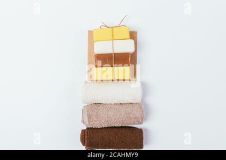 Stack bars of soap and towels on white background, flat lay composition set for personal hygiene. Stock Photo