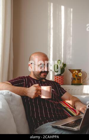 young people having a good time at home. listening to music, drinking coffee and tea. Resting teenager running with tablet and leptop in hands. Stock Photo