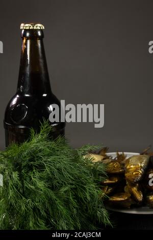 A bottle of dark beer and a plate of fish. On a dark background. Stock Photo