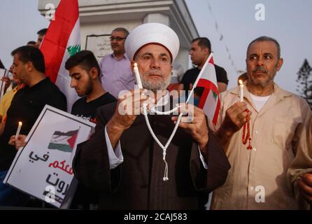 Gaza, Palestine. 06th Aug, 2020. A Palestinian man holds a Lebanese flag and a lit candle during a solidarity march with the Lebanese after a huge explosion at Beirut Port. Credit: SOPA Images Limited/Alamy Live News Stock Photo