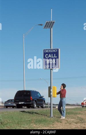 Woman uses solar-powered emergency phone on highway shoulder in Austin, Texas.  Model Release. ©Bob Daemmrich Stock Photo